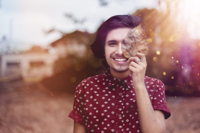 person with leaf playfully covering face