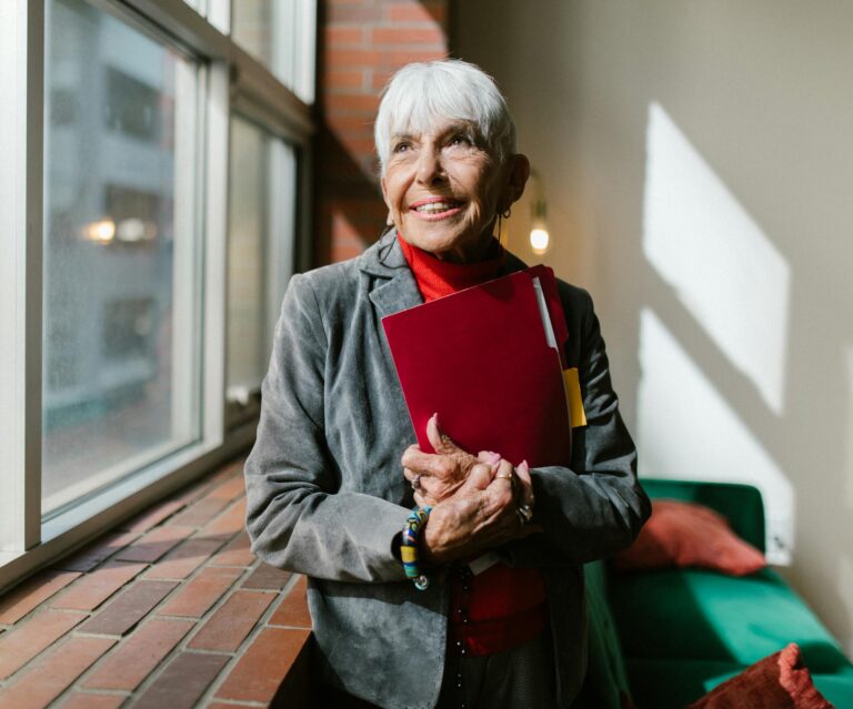 Elderly Woman Smiling Holding a Red Folder