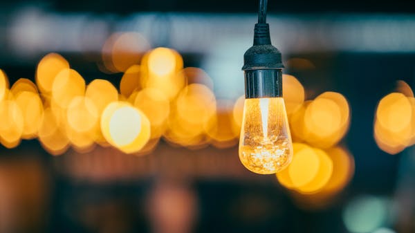 A close-up of a glowing Edison light bulb against a bokeh backdrop, creating a warm ambient atmosphere.