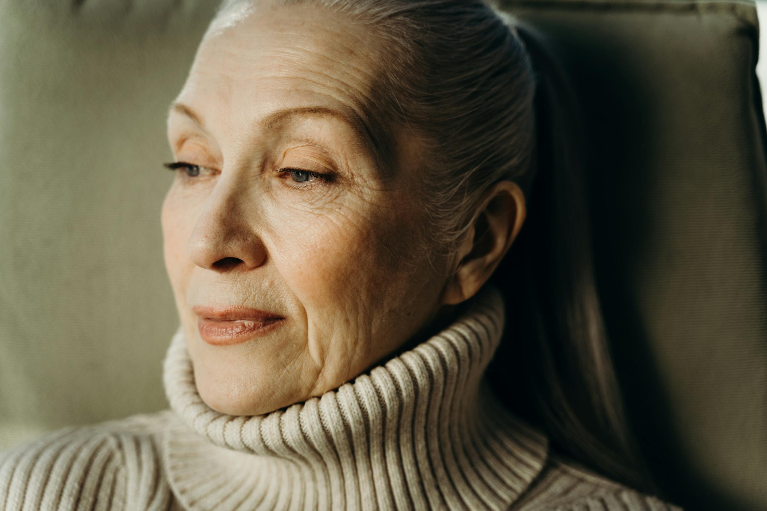 Close-up of a thoughtful senior woman wearing a cozy turtleneck sweater.