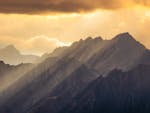 A breathtaking view of sun rays illuminating the Italian Alps at sunset.