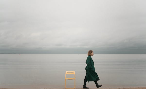 A solitary woman walks by the ocean, capturing calm and introspective solitude.