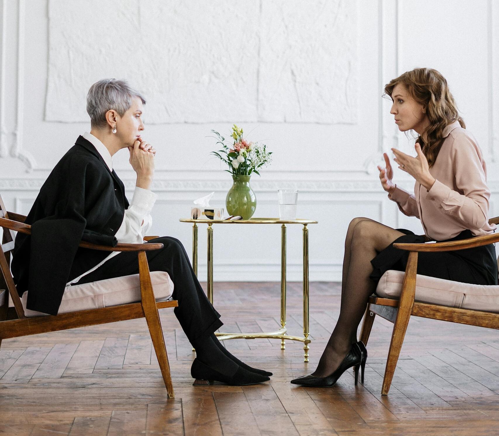 Two women engaged in a counseling session in a bright, modern loft setting.