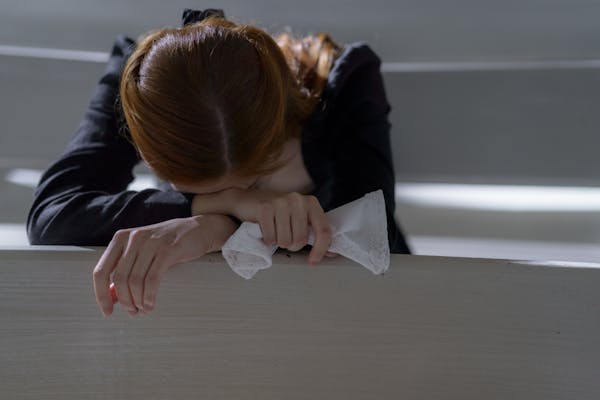 A woman crying while leaning on a bench
