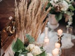 An elegant funeral arrangement with a wooden coffin, flowers, and candlelight indoors.