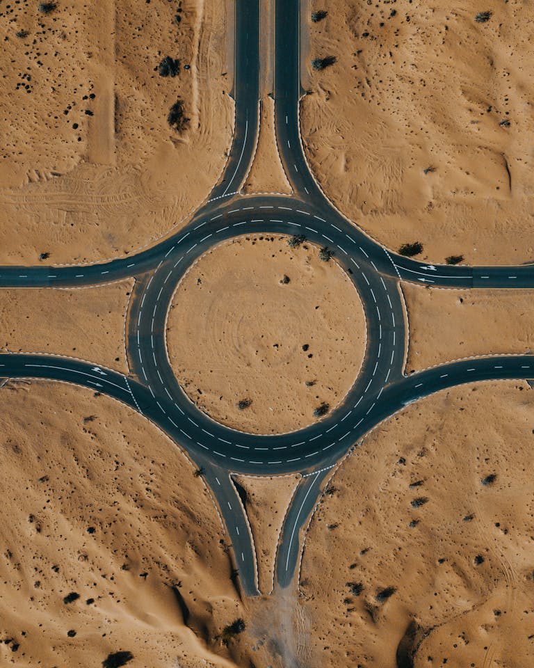Top view of a desert roundabout surrounded by sand and roads.