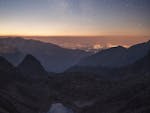 Breathtaking view of Slovakia's High Tatras at night with starry sky and tarn.