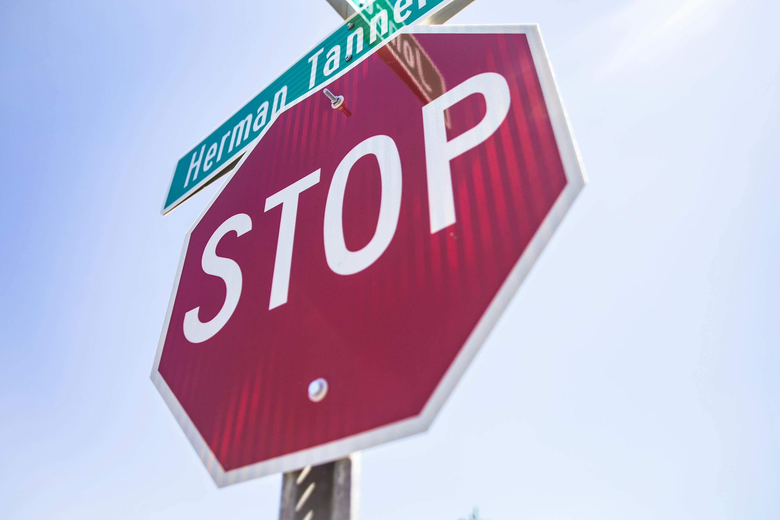 Red stop sign with street name visible against clear blue sky.