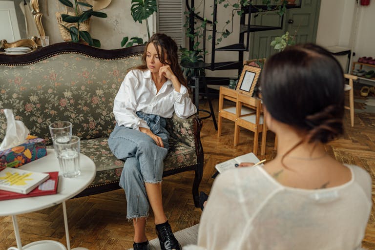 A thoughtful counseling session between a psychologist and a patient in a cozy, well-decorated room.