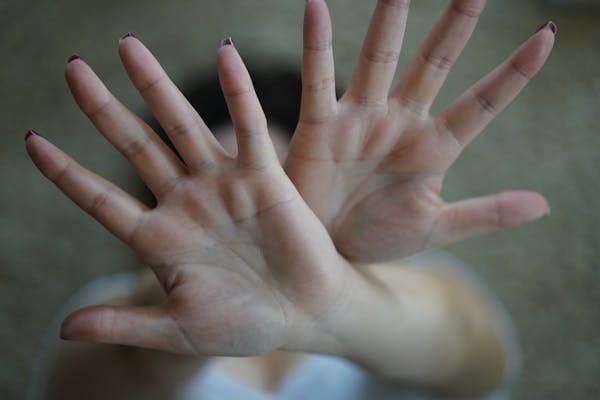 Close-up image of two hands raised with palms open in a stop gesture, emphasizing disapproval.