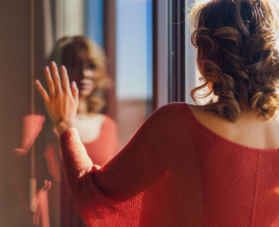 Back view of a woman in red clothing, gazing at her reflection in Madrid.