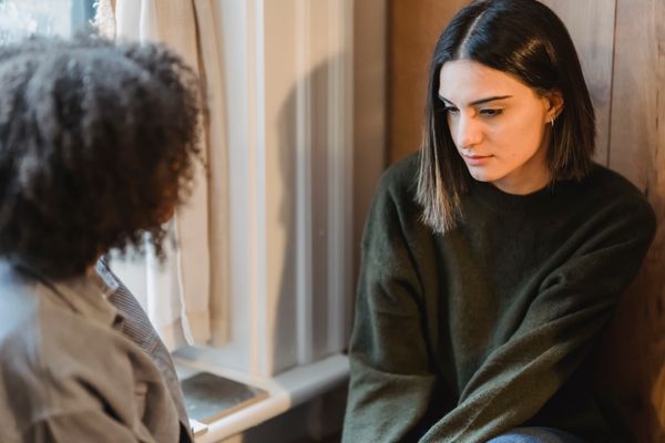 From above of crop anonymous female listening friend sharing news at home in daytime